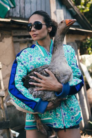 Téléchargez les photos : Jeune agricultrice à la mode tient l'oie - en image libre de droit