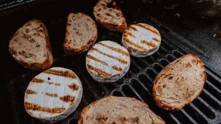 Photo for Grilled camembert, on old dark grille. Shallow dof - Royalty Free Image