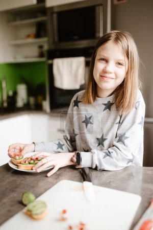 Téléchargez les photos : Petite fille faisant le petit déjeuner à la maison. - en image libre de droit