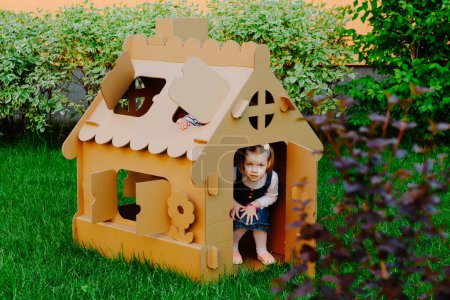 Foto de Los niños juegan en una casa de cartón. Niño divirtiéndose al aire libre - Imagen libre de derechos
