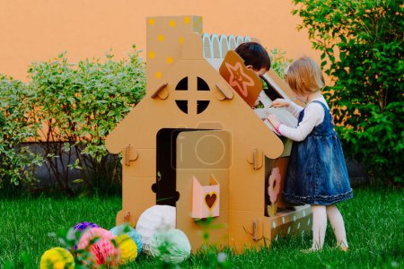 Photo for Children painting on the cardboard playhouse - Royalty Free Image