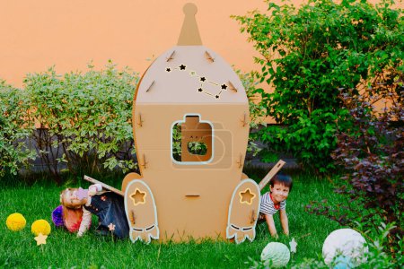 Photo for Children play outdoor. Healthy activity. Summer vacation fun. Child playing in sunny park. Children are having fun at cardboard rocket. - Royalty Free Image