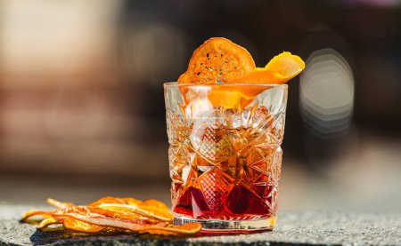 Téléchargez les photos : Délicieux cocktail à l'ancienne dans le verre gravé avec des tranches de glace et d'orange, fond en bois foncé. Dof peu profond - en image libre de droit