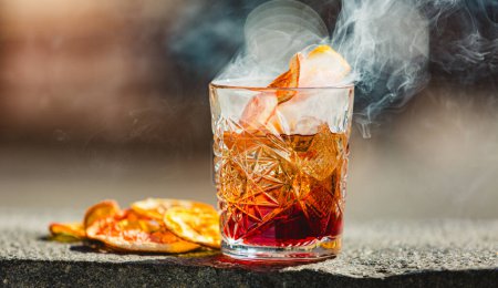 Photo for Delicious old fashion cocktail in the etched glass with ice and orange slices, dark wooden background. Shallow dof - Royalty Free Image