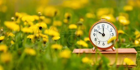 Alarm clock in the flowers. Spring forward, springtime or daylight savings time banner.