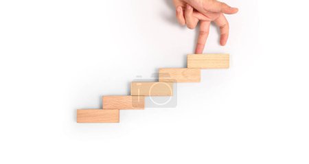 Hand liken person stepping up a toy staircase wood