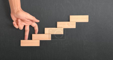 Comparación de mano persona escalando una escalera de juguete madera