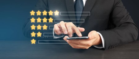 Photo for Man holding smartphone device and touching screen with five star rating feedback icon - Royalty Free Image