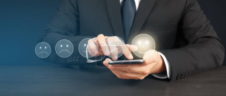 Téléchargez les photos : Homme tenant smartphone appareil et écran tactile avec cinq étoiles évaluation icône de rétroaction - en image libre de droit