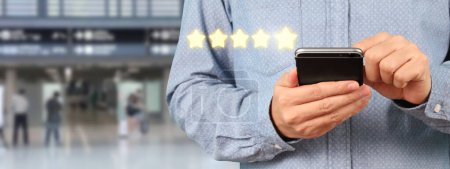 Téléchargez les photos : Homme tenant smartphone appareil et écran tactile avec cinq étoiles évaluation icône de rétroaction - en image libre de droit
