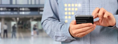 Photo for Man holding smartphone device and touching screen with five star rating feedback icon - Royalty Free Image