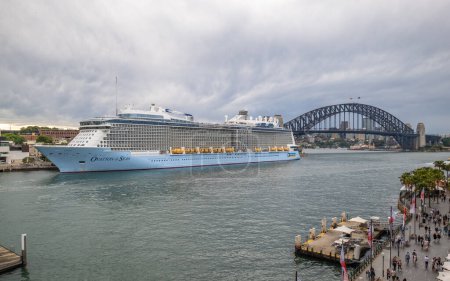 Photo for Circular Quay, Sydney, Australia - 7th December 2022: The cruise ship Ovation Of The Seas of Royal Caribbean International is moored at Circular Quay in Sydney, Australia, with the Sydney Harbour Bridge in the distance. - Royalty Free Image