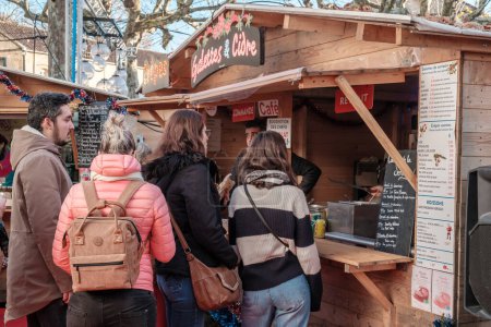 Foto de Sarlat-la-Caneda, Nouvelle-Aquitaine, Francia - 16 de diciembre de 2023: Gente haciendo cola en un puesto de venta de galettes y crepes en el mercado navideño de Sarlat-la-Caneda, en la región de Dordoña, Francia - Imagen libre de derechos