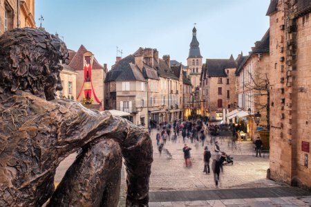 Photo for Sarlat-la-Caneda, France - 16th December 2023: "Le Badaud" or Onlooker, a bronze sculpture by Gerard Auliac, watches over Christmas shoppers in the market square at Sarlat in the Dordogne region of France - Royalty Free Image