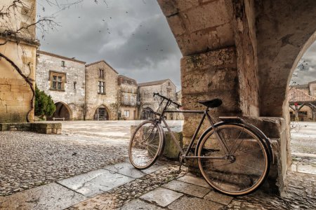 Photo for A bicycle under the covered walkway surrounding the market square of the 13th century bastide of Monpazier in the Dordogne region of France - Royalty Free Image