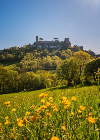 Morning sunshine on the medieval fortified village of Turenne in the Correze department of France with buttercups in a field in the foreground