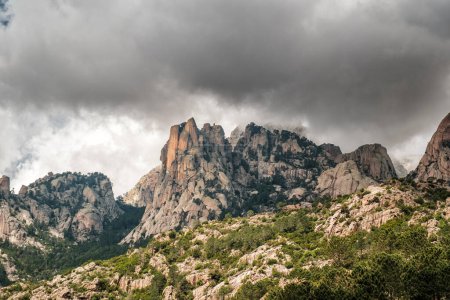 Dunkle Wolken über den Aiguilles de Bavella, nadelförmige felsige Berggipfel umgeben von Kiefernwäldern und Macchia im Zentrum Korsikas