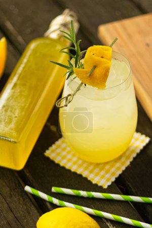 Citrus lemon lime homemade lemonade in a bottle and a glass with fruit decoration on wooden table in nature