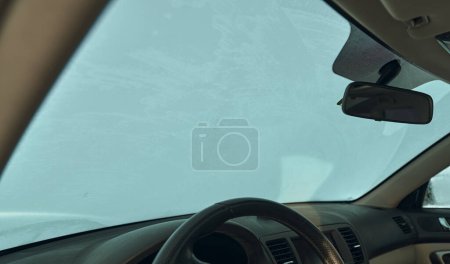 Photo for Frosted car glass. snow-covered car windshield. View from inside the car during a winter day. Concept of bad visibility during the winter season. car interior. - Royalty Free Image