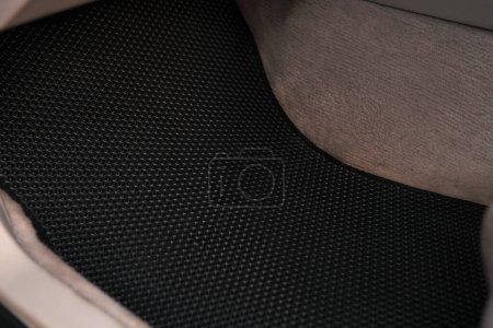 Foto de Luxury car with white leather interior with high-quality EVA floor mats in black color. Close-up of black ethylene vinyl acetate car floor mat. - Imagen libre de derechos
