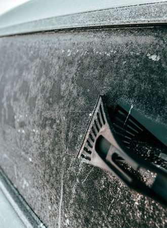 Photo for Man is cleaning an icy window on a car with an ice scraper. Cold snowy and frosty morning. Focus on the ice scraper. - Royalty Free Image