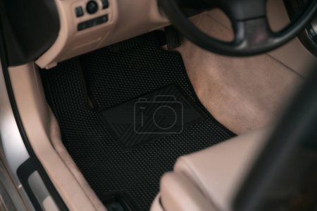 Foto de Driver-side black floor mats made of ethylene vinyl acetate shortened for EVA. Dark floor mats in the light interior of the car. - Imagen libre de derechos