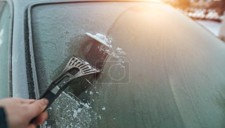 Foto de Cleaning the windshield from ice with a plastic ice scraper. - Imagen libre de derechos