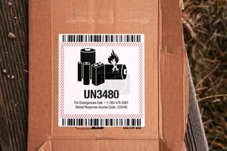 Foto de Battery warning label on a package for transporting flammable metal lithium batteries. Danger UN3480 sign on the envelope. - Imagen libre de derechos