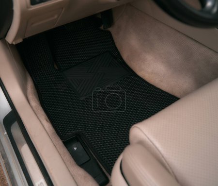 Foto de Driver-side black floor mats made of ethylene vinyl acetate shortened for EVA. Dark floor mats in the light interior of the car. - Imagen libre de derechos