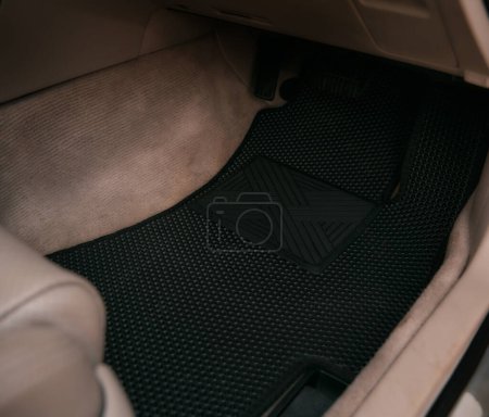 Foto de Luxury car with white leather interior with high-quality EVA floor mats in black color. Close-up of black ethylene vinyl acetate car floor mat. - Imagen libre de derechos