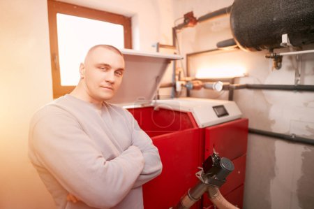 Foto de Calentamiento futuro sostenible. Hombre usando horno de calefacción de pellets. Retrato del trabajador en la sala de calderas. - Imagen libre de derechos
