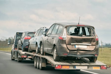 Tow truck with broken car on country road. Tow truck transporting car on the highway. Car service transportation concept.