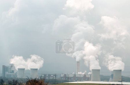 Photo for Two large concrete cooling towers with smoke coming out of them. Coal power plant. - Royalty Free Image