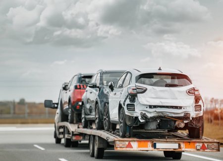 Photo for Roadside Assistance on the Highway After a Traffic Accident. side view of the fltabed tow truck with a damaged vehicles after a traffic accident. - Royalty Free Image