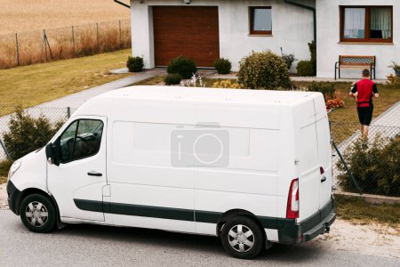 A white delivery van is parked on the roadside. Parcel logistics concept. Door-to-door overnight delivery company.