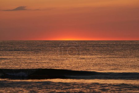 Photo for The glowing sun sinking on the horizon of the sea or ocean - Royalty Free Image