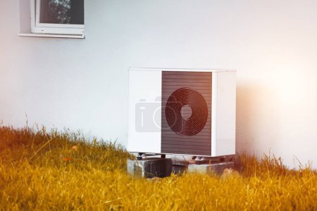 Téléchargez les photos : Pompe à chaleur Air Source installée à l'extérieur d'une maison. Thermopompe moderne pour le chauffage et l'eau chaude devant le nouveau bâtiment résidentiel - en image libre de droit