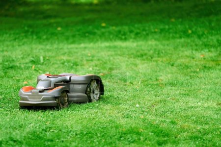 Téléchargez les photos : Robotique tondeuse à gazon sur herbe, vue latérale. Gros plan isolé de la tondeuse automatique. Entretien intelligent des pelouses. Taille-herbe électronique. - en image libre de droit