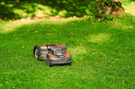 Téléchargez les photos : Entretien intelligent des pelouses. Robotique tondeuse à gazon en action. Taillage de gazon sans effort. Gros plan d'une tondeuse à gazon automatique - en image libre de droit