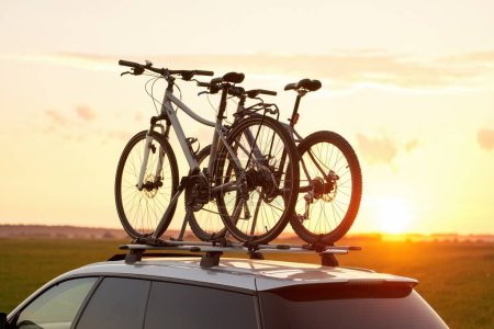 Foto de Coche de pasajeros con dos bicicletas montadas en el techo. Bicicletas de techo. Transporte de material deportivo. - Imagen libre de derechos