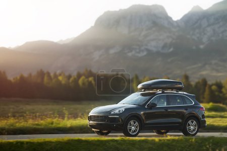 Photo for Expensive family SUV with Luggage box mounted on the roof. Extra Capacity for the Road. Black SUV with Roof Rack. - Royalty Free Image