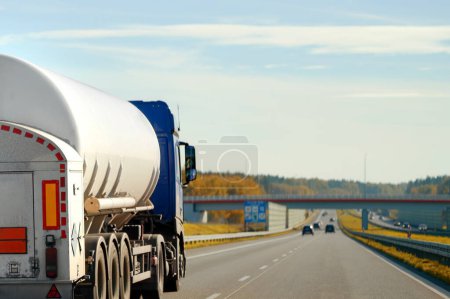 Transporte de mercancías peligrosas en camión semirremolque con tanque de propano. El camión cisterna tiene una vista lateral y muestra etiquetas de peligro para líquidos de alta temperatura y peligros diversos. El camión sigue el ADR