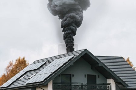 Photo for Dark smoke comes out of the chimney of a modern house in winter. Heating with solid fuel. The concept of environmental pollution - Royalty Free Image