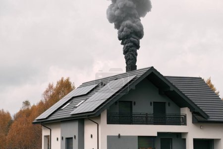 Photo for A house with a chimney emits black smoke in the cold air, causing environmental pollution - Royalty Free Image