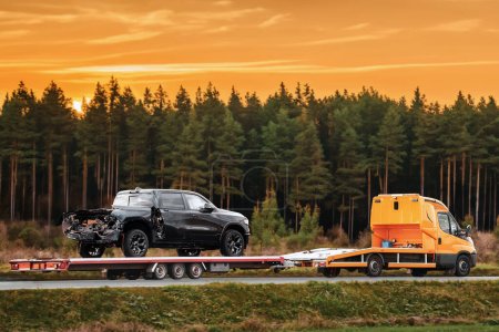Photo for A tow truck evacuates a broken pick-up truck on a flatbed trailer from the interstate highway, after an accident that required emergency service and assistance. - Royalty Free Image