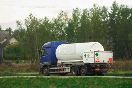 Photo for Dangerous goods transportation by semi truck with propane tank. The tank truck has a side view and shows hazard labels for high-temperature liquid and miscellaneous hazards. The truck follows the ADR - Royalty Free Image