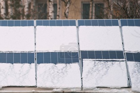 Snow melting from covered solar photovoltaic panels installed on house roof for producing sustainable electrical energy. Concept of low effectivity of renewable electricity in northern region climates