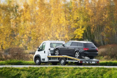 Photo for Emergency roadside assistance in action as a tow truck carries a broken down SUV on the highway. - Royalty Free Image
