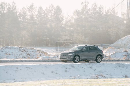 Téléchargez les photos : Une voiture couverte de sel sur une route glacée. Le véhicule présente des signes de corrosion et de dommages causés par le réactif routier. Le temps est froid et neigeux en hiver. - en image libre de droit