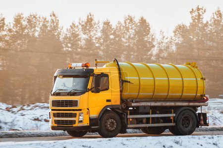 Téléchargez les photos : Cadre hivernal froid et autoroute enneigée tiennent un camion jaune vif vibrant transportant un pétrolier vert. - en image libre de droit